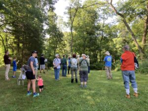 Group of people in summer clothes standing near trees.